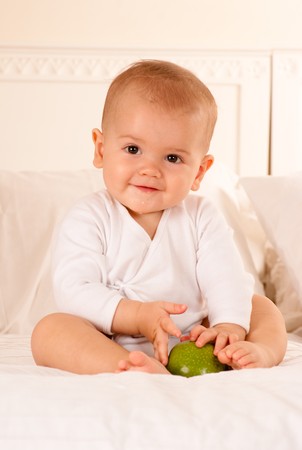 
Cheerful baby on a bodysuit holding a green apple
の写真素材