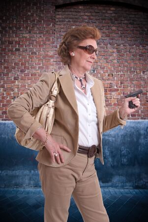 
Senior lady with sunglasses and a gun in her hand on an urban background
の写真素材