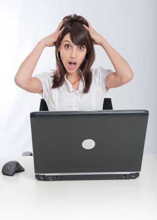 

Young woman sitting at her desk with her laptop with an alarmed expression

の写真素材