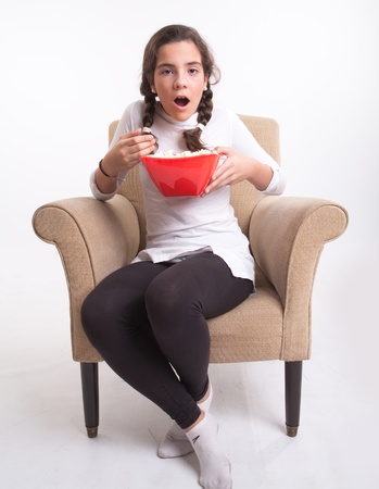 
Girl sitting on an armchair with a popcorn bowl looking open-mouthed
の写真素材