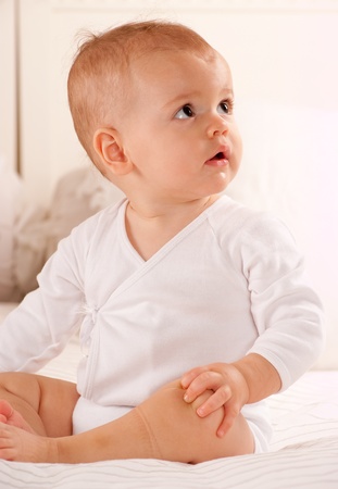 
Cute baby sitting on a bed dressed in a bodysuit
の写真素材