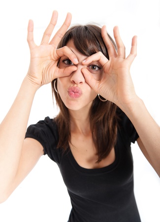 
Young brunette making a face, pretending to wear glasses and blowing a  kissing

の写真素材