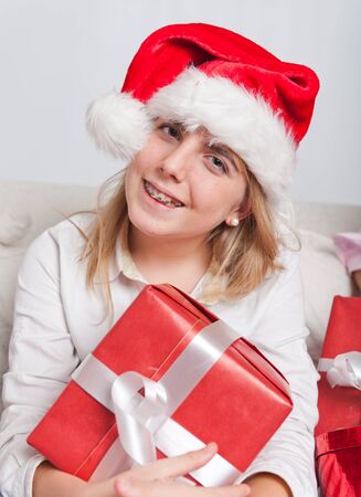 Young teenage girl wearing a Santa hat holding a present の写真素材