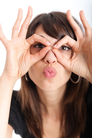 
Young brunette making a face, pretending to wear glasses and blowing a  kissing

の写真素材
