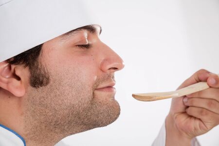 
Male cook delightfully smelling the contents of a wooden spoon
の写真素材