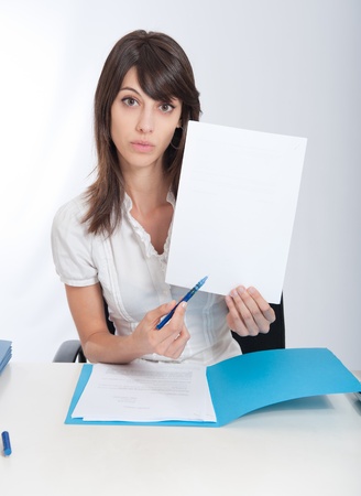 

Young woman at a desk pointing with her pen to a blank paper. Ideal for inserting your own message
の写真素材