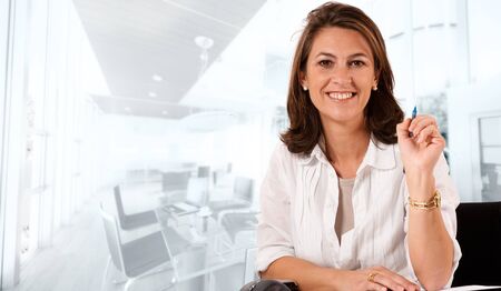 Smiling woman sitting at her desk on an office environmentの写真素材