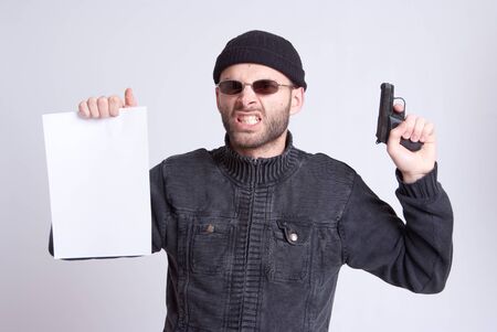 
Dangerous looking man holding a gun and a blank paper sheet
の写真素材