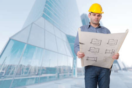 Man with helmet holding a roll of blueprints in a financial district
