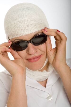 Portrait of a woman with a bandaged head hiding behind sunglassesの写真素材