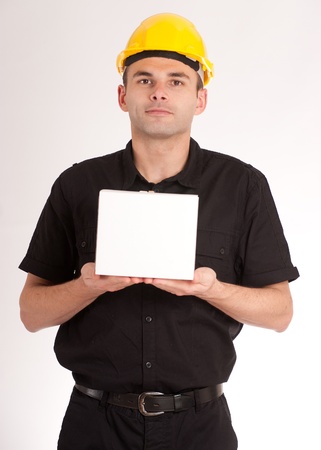 Man in black wearing a yellow safety helmet holding a white boxの写真素材