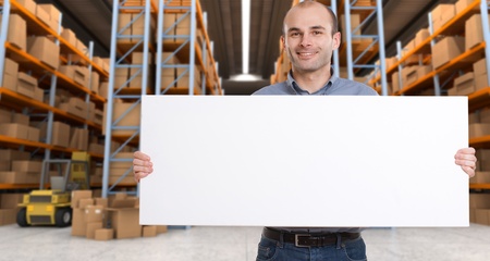 A man holding a blank board in a distribution warehouse, ideal for inserting your own messageの写真素材