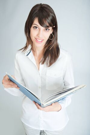 

Young brunette wearing a white shirt reading a book

の写真素材
