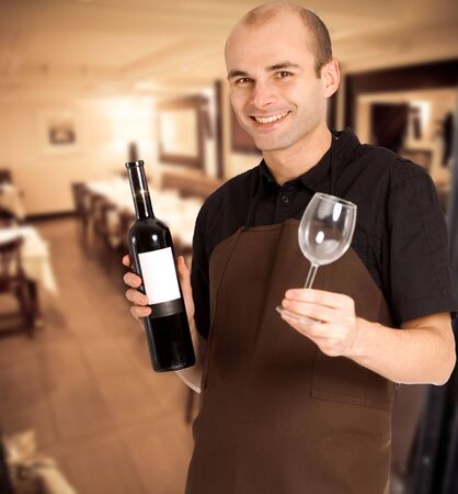 Smiling sommelier presenting a wine bottle with a blank label and a glass in a restaurantの写真素材