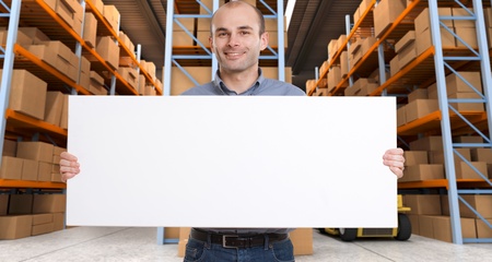 A man holding a blank board in a distribution warehouse, ideal for inserting your own messageの写真素材