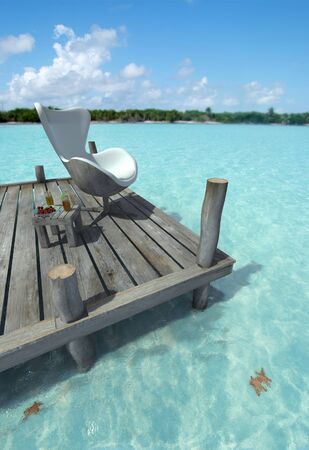 Designers chair on a peer, side table with refreshments and a beautiful Caribbean oceanの写真素材