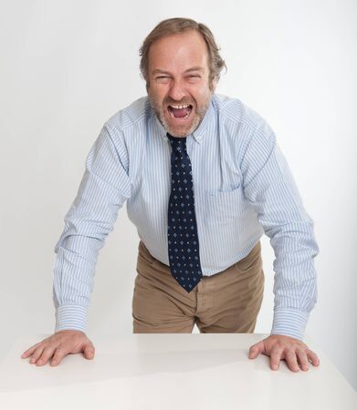 Angry looking business man leaning on a tableの写真素材