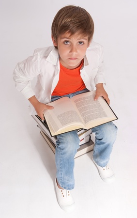 Schoolboy sitting, on a pile of books reading one, aerial viewの写真素材