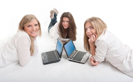 Three girls lying on the floor using each a laptop の写真素材