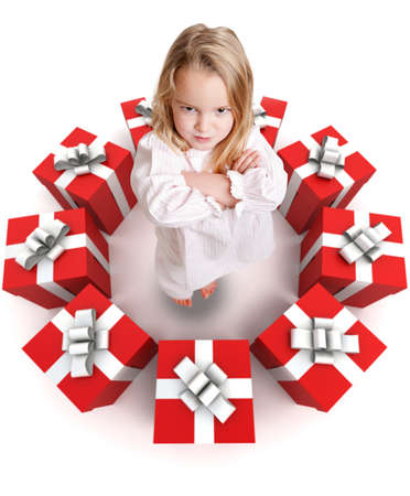 Sulking funny little girl in pajamas surrounded by a ring of presentsの写真素材