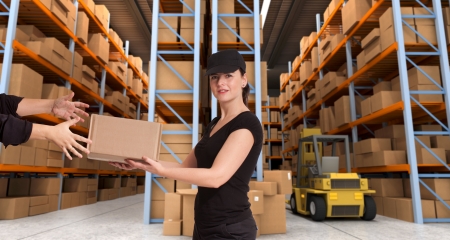 Female courier carrying a parcel in a distribution warehouseの写真素材
