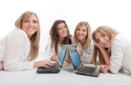 Four smiling girls on the floor with mini computers and pc tabletsの写真素材