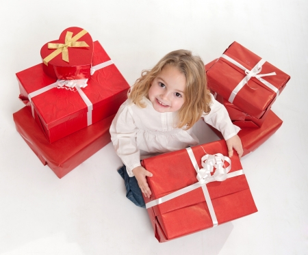 Little girl in white surrounded by red and white gift boxesの写真素材