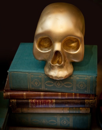 Golden skull on top of a pile of old booksの写真素材