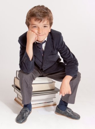 
Cute young schoolboy sitting on top of a pile of books
の写真素材