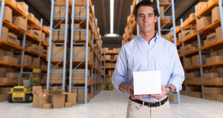 Young man holding a blank white box in a distribution warehouseの写真素材