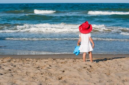 
Little girl with a red hat and blue bucket looking to the ocean
の写真素材