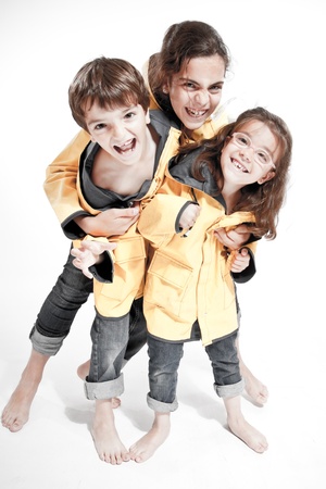 
Three young siblings barefoot wearing jeans and yellow raincoats
の写真素材
