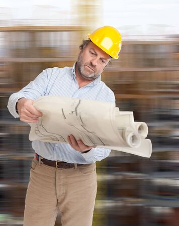 Man with helmet and blueprints and a blurry backgroundの写真素材
