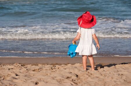 
Little girl with a red hat and blue bucket looking to the ocean
の写真素材