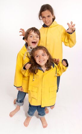 
Three young siblings barefoot wearing jeans and yellow raincoats
の写真素材