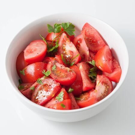 Tomato and parsley salad in a white bowlの写真素材