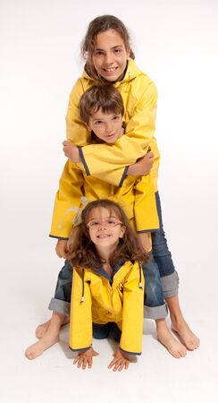 
Three young siblings barefoot wearing jeans and yellow raincoats
の写真素材
