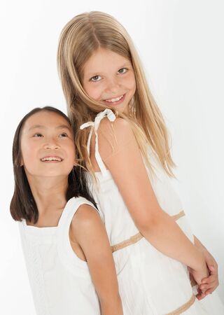 Two little girls, grinning, back to back の写真素材