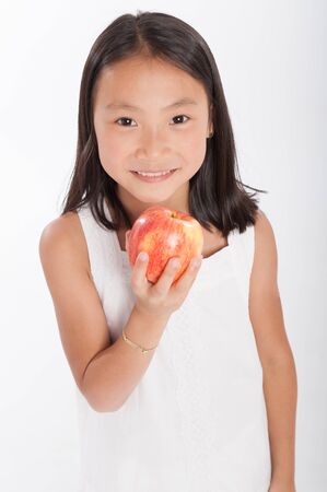Cute little Asian girl holding an appleの写真素材