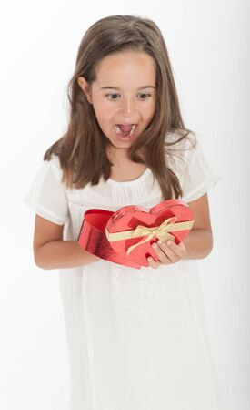 Little girl holding a heart shaped gift boxの写真素材