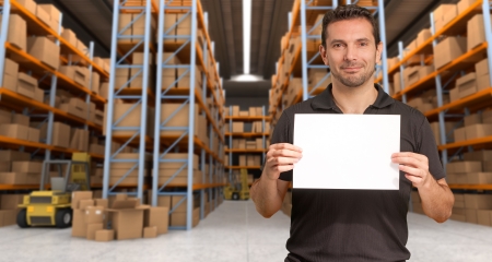 A man holding a blank paper in a distribution warehouse, ideal for inserting your own messageの写真素材