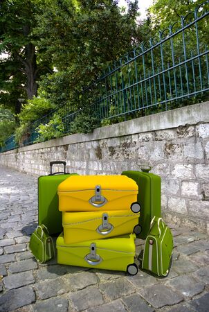 A pile of luggage on a town street by a parkの写真素材