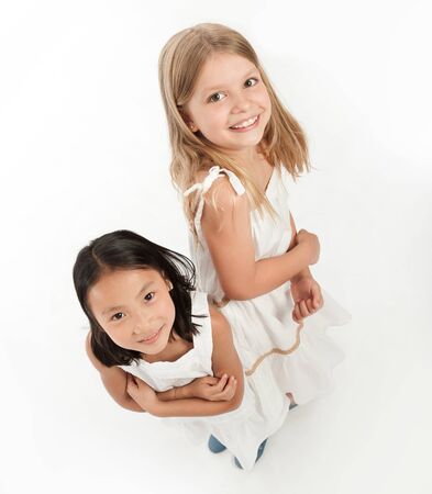 Two little girls, grinning, back to back の写真素材