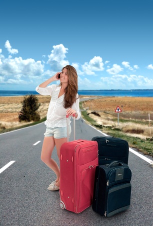 Young female tourist with her baggage,  talking on the phone in the middle of the roadの写真素材