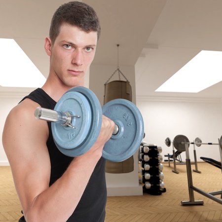 Young man in a gym lifting a dumbbellの写真素材