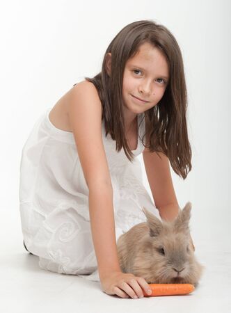 Young girl feeding a carrot to a baby rabbitの写真素材