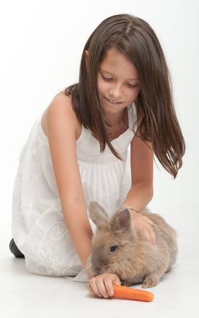 Young girl feeding a carrot to a baby rabbitの写真素材