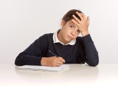 
Schoolgirl writing on a notebook with an stressed expression
の写真素材