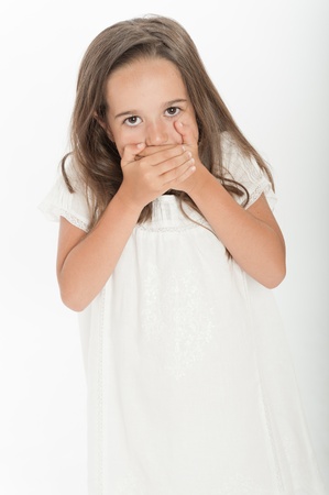 Cute little girl covering her mouth with her handsの写真素材