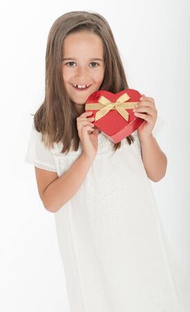 Little girl holding a heart shaped gift boxの写真素材